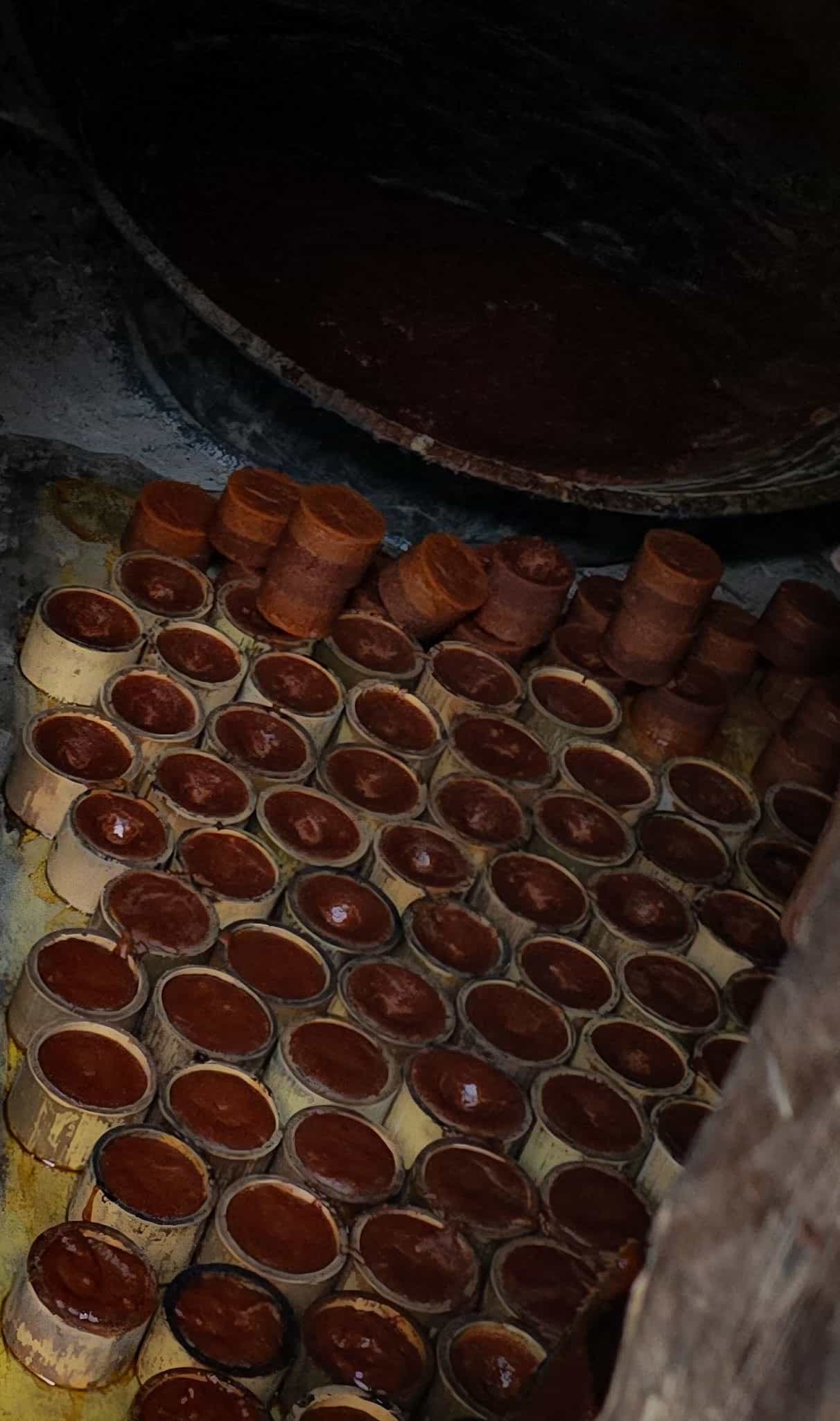 Dozens of bamboo moulds filled with setting palm sugar, some already turned out as solid blocks