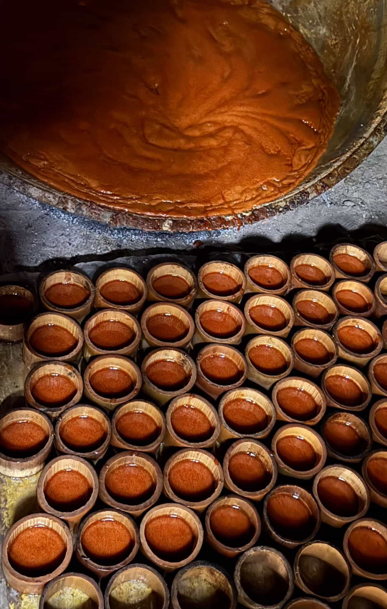 Golden palm sugar syrup hot in the kettle above rows of bamboo moulds filled to the brim